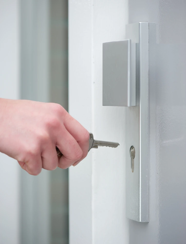 Commercial Locksmith services A professional Rapid Locksmiths technician testing a silver key in a modern euro profile cylinder lock on a white door