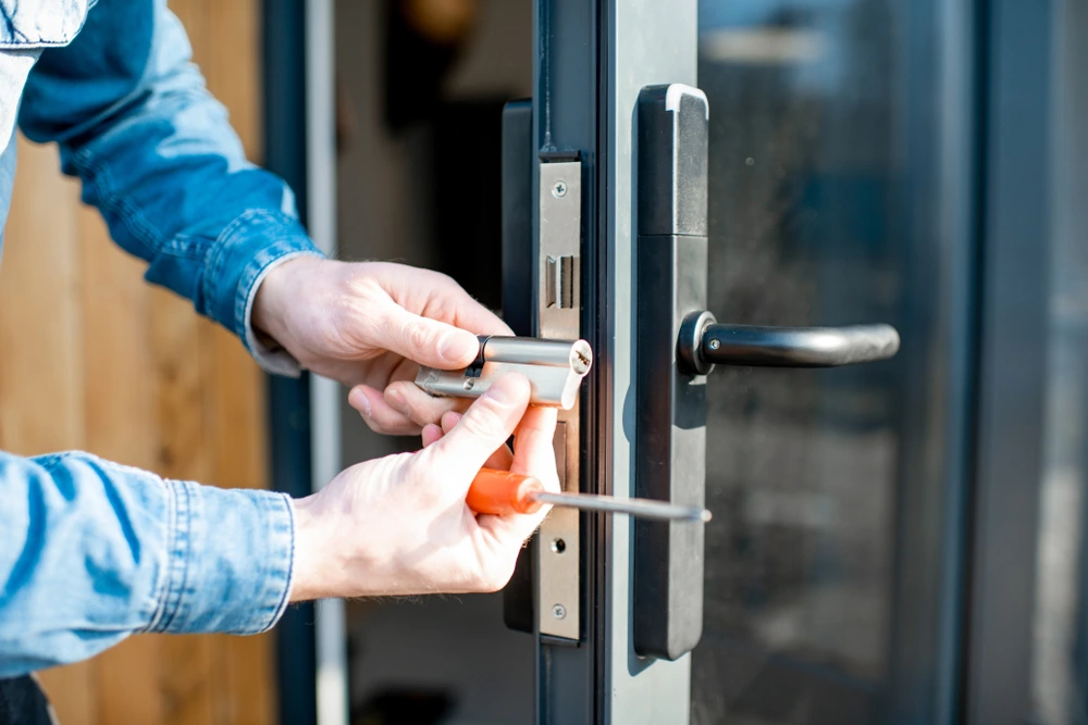Professional locksmith from Rapid Locksmiths installing a new euro cylinder lock into a modern black door handle assembly